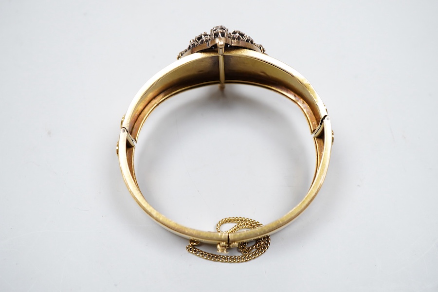 A Victorian gold and diamond bracelet, the hinged cuff decorated with wire scrollwork, centring on an oval motif set with rose-cut diamonds, inner circumference approximately 17cm, width at front 3.8cm, gross weight appr